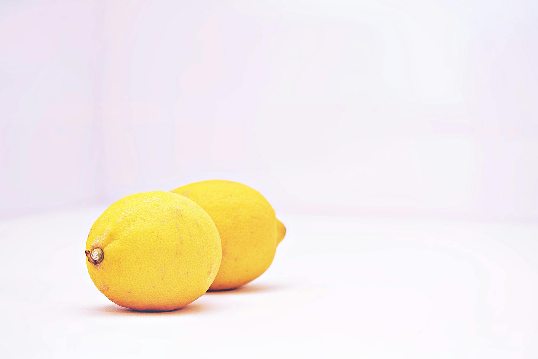 Deux citrons vibrants placés sur un fond blanc minimaliste, incarnant la fraîcheur et la simplicité