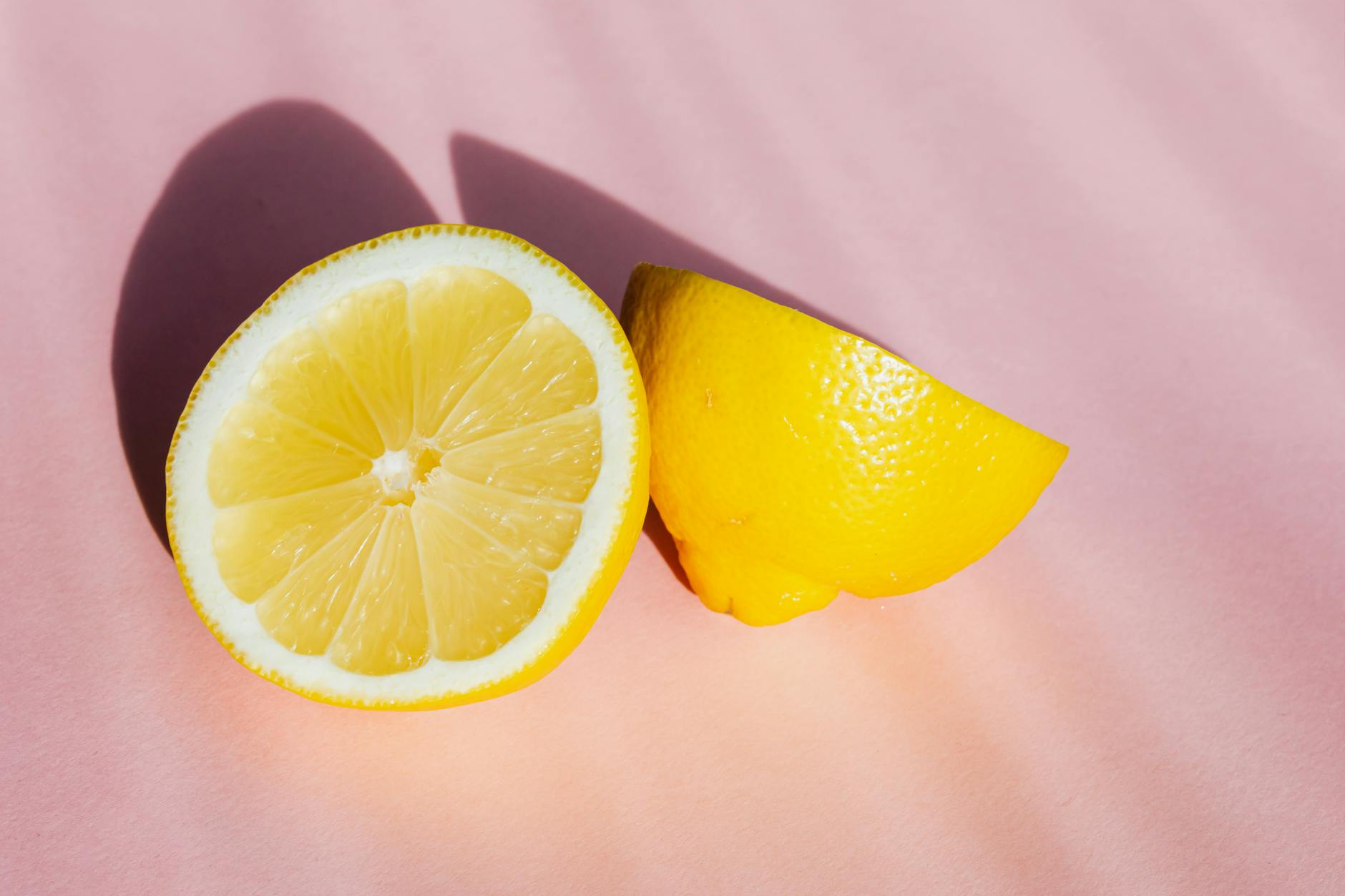 Moitiés de citron frais et juteux sur un fond rose ensoleillé