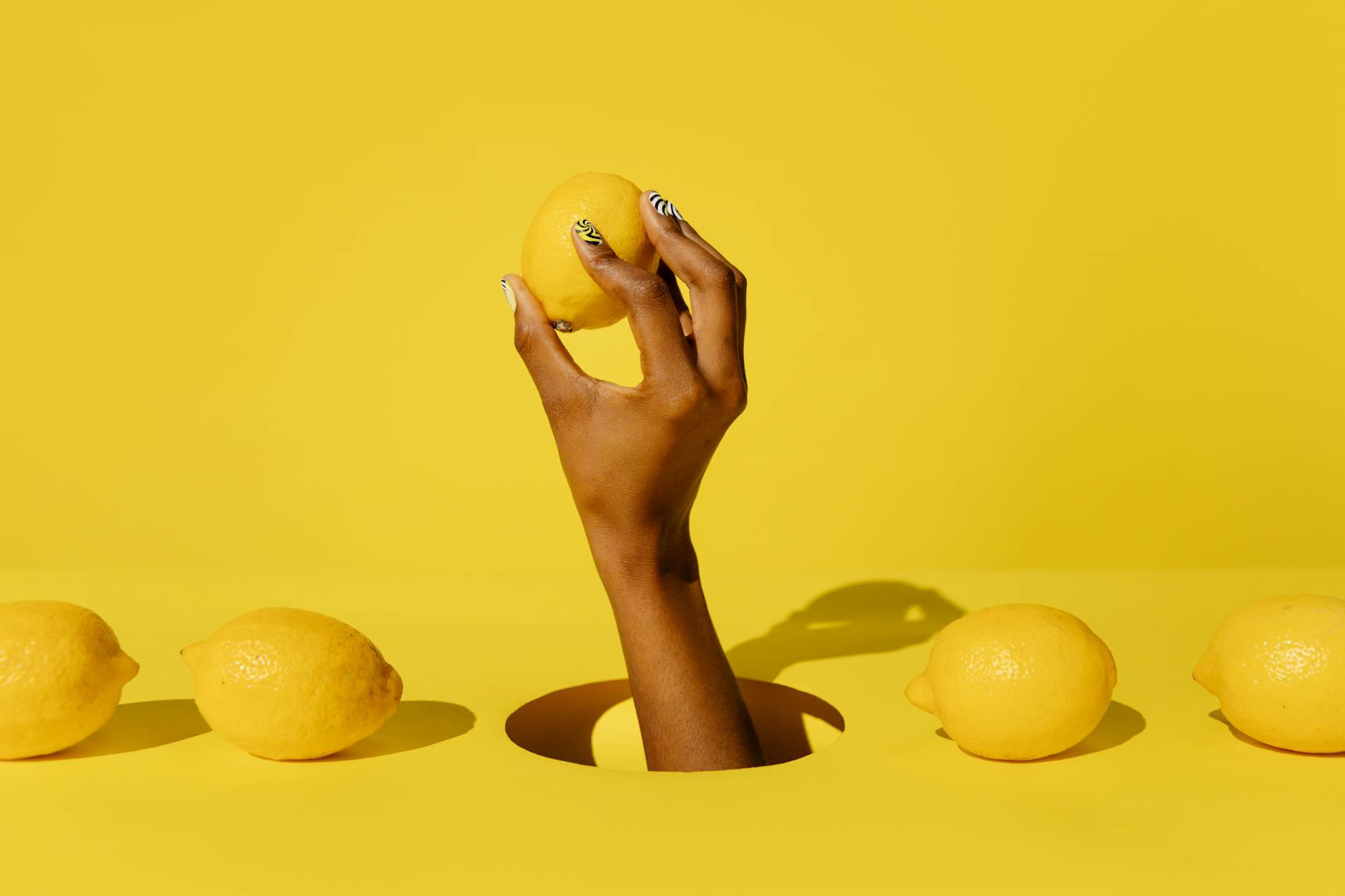 Une main tenant un citron frais contre un fond jaune vif, symbolisant la fraîcheur et la sensualité retrouvées