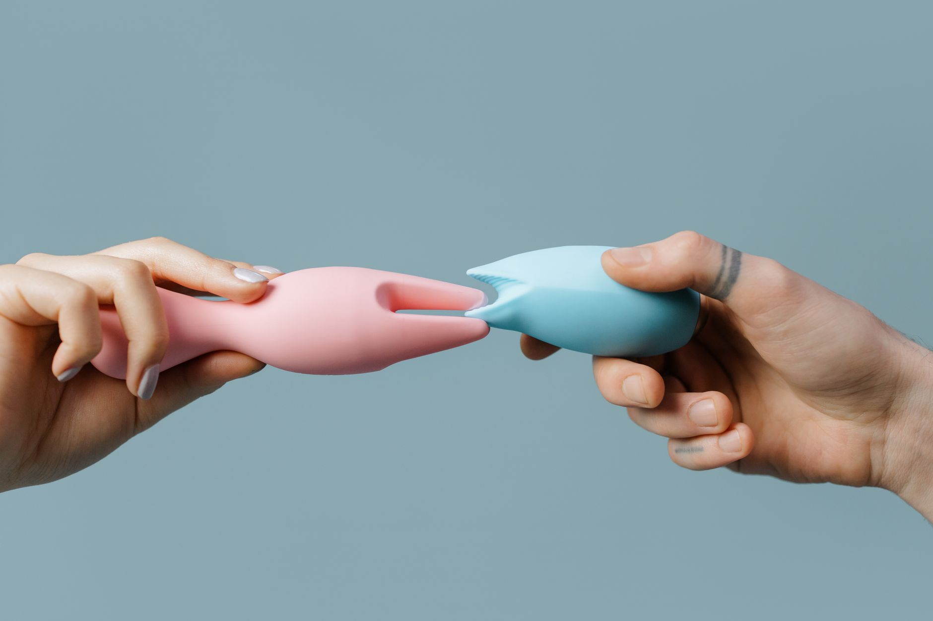 Gros plan des mains tenant un vibromasseur bleu élégant sur fond violet