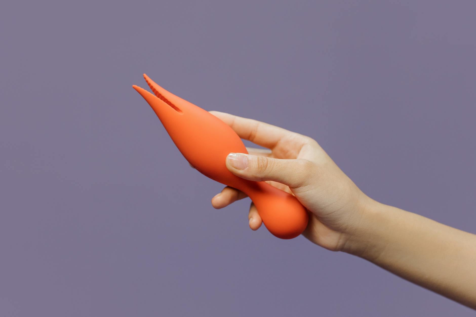 Une main tenant un vibromasseur citron contre un fond pourpre minimaliste, affichant la sensualité moderne