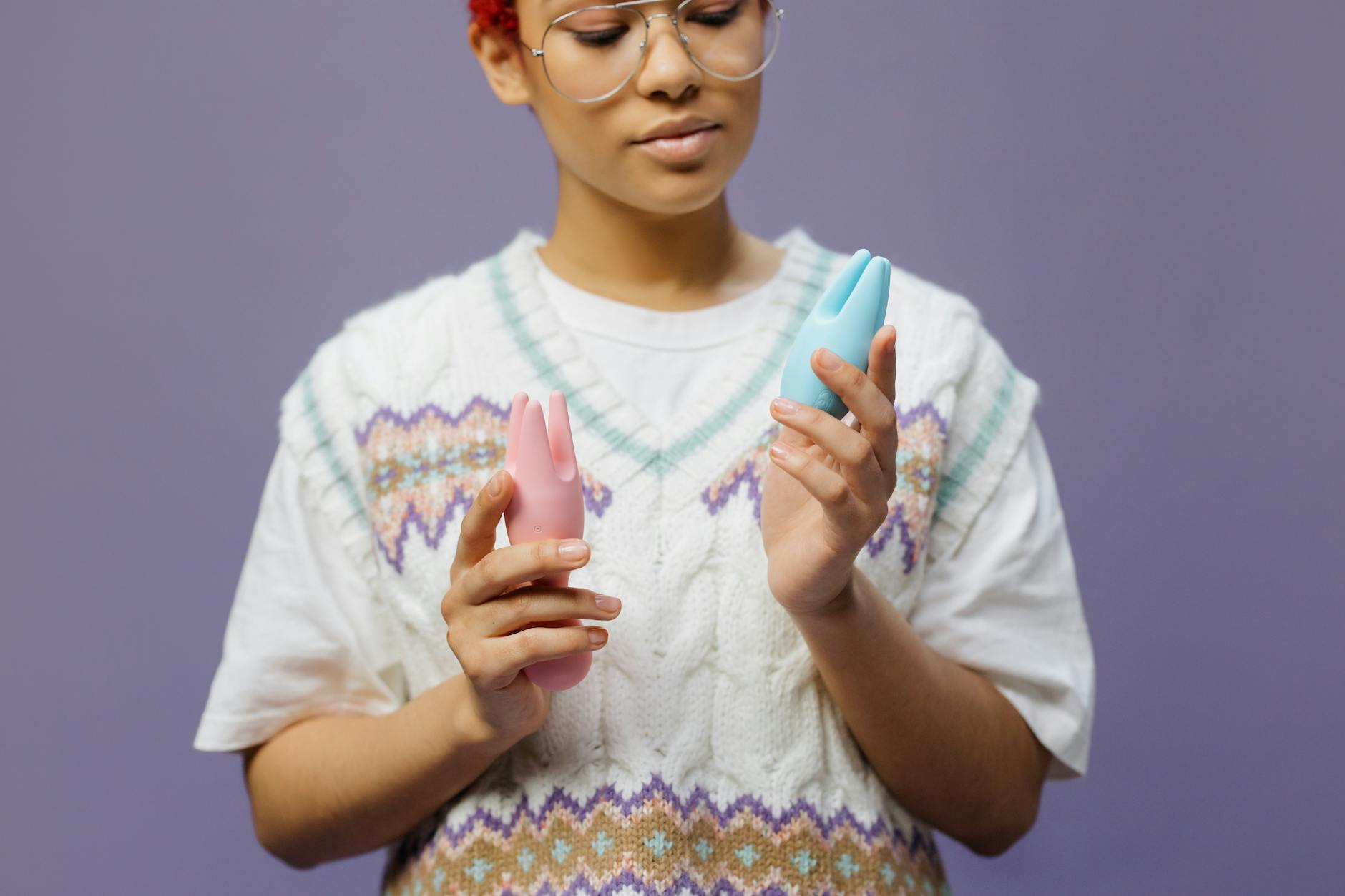 Une femme tenant un vibromasseur clitoridien bleu et rose avec une expression réfléchie