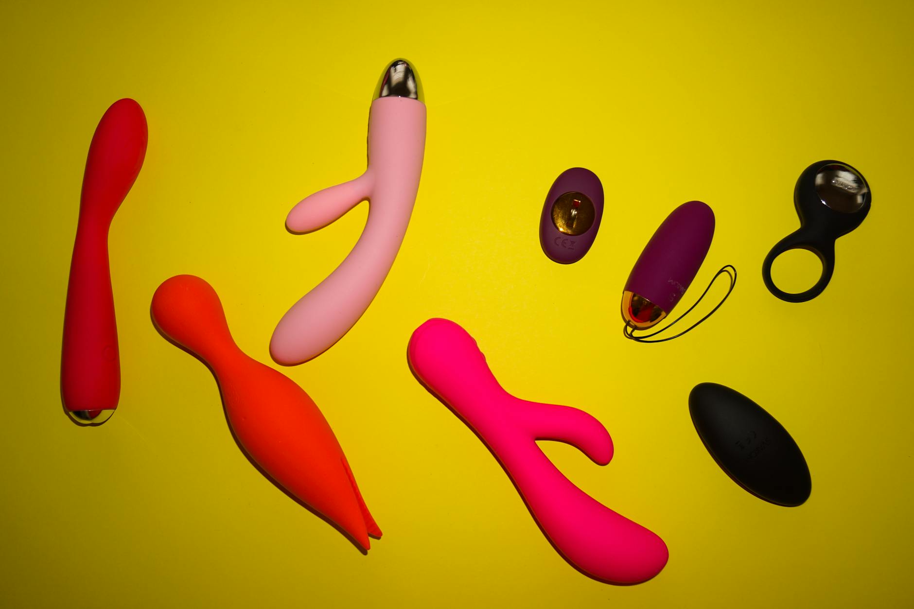 Arrangement vibrant de vibromasseurs colorés sur une surface jaune éclatante, mettant en avant la diversité et le design
