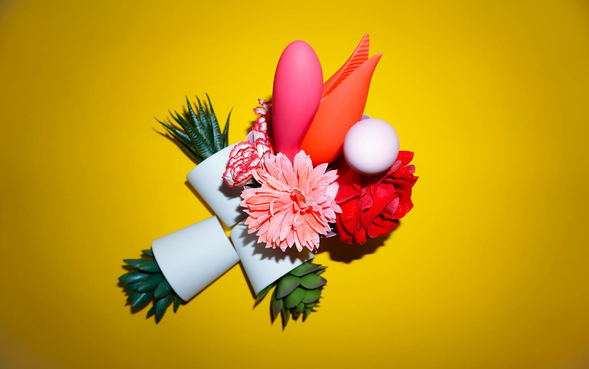 Arrangement coloré de fleurs et objets abstraits sur fond jaune vif