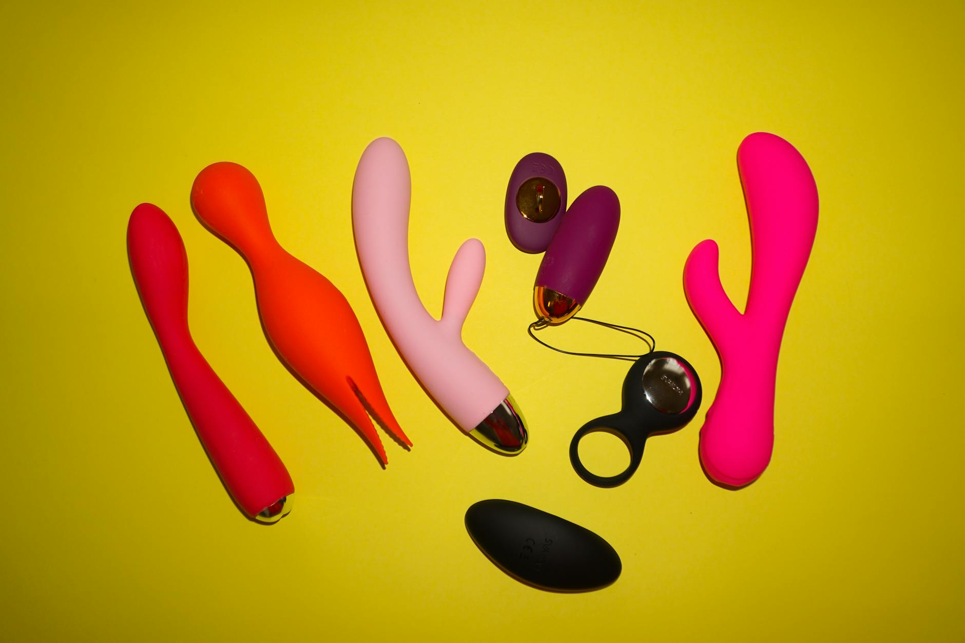 Studio présentant des vibromasseurs colorés sur fond jaune vif, mettant en avant diverses formes et designs
