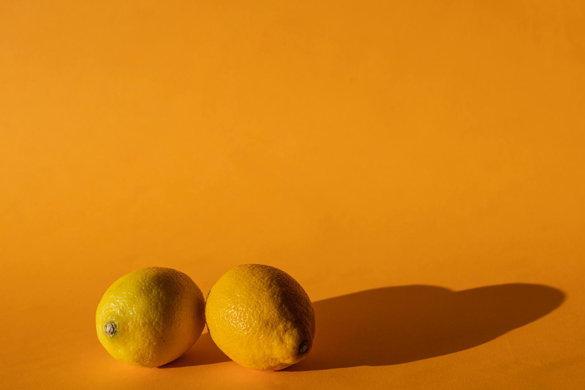 Gros plan d'une main tenant un vibromasseur orange sur un fond violet minimaliste